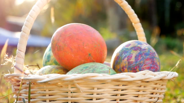 Close-up-of-basket-with-colourful-a-easter-eggs-on-grass-in-sunshine-background