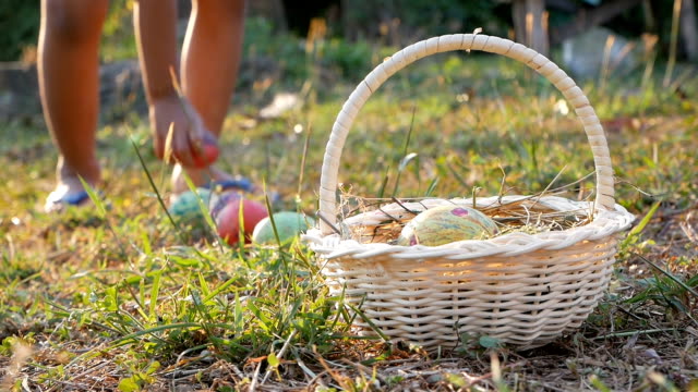 Close-up-of-a-children-take-easter-eggs-into-basket-in-sunshine-background