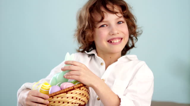 A-child-holds-a-Easter-bunny-and-a-set-of-decorative-Easter-eggs.-The-boy-laughs-cheerfully.-Slow-Motion