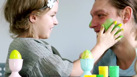 Happy-easter.-Father-and-daughter-paint-each-other's-eggs-and-faces.-Family-jokes