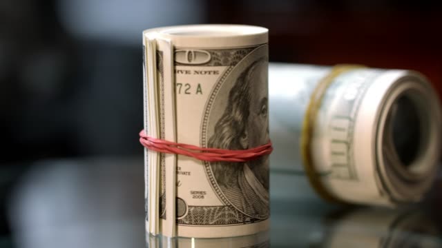Cash-money-rolls-on-table.-Rotating-rolls-of-hundred-american-dollar-bills