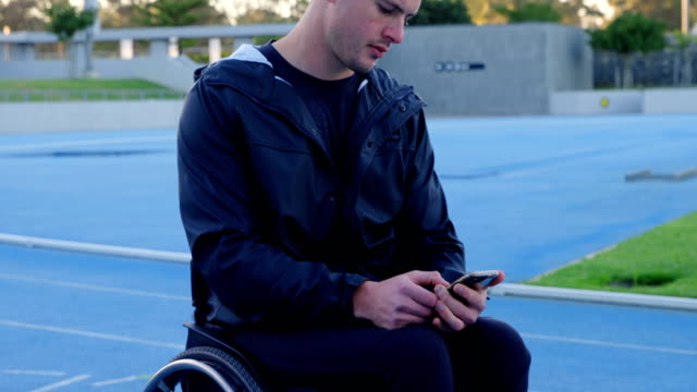 Disabled-athletic-using-mobile-phone-at-sports-venue-4k