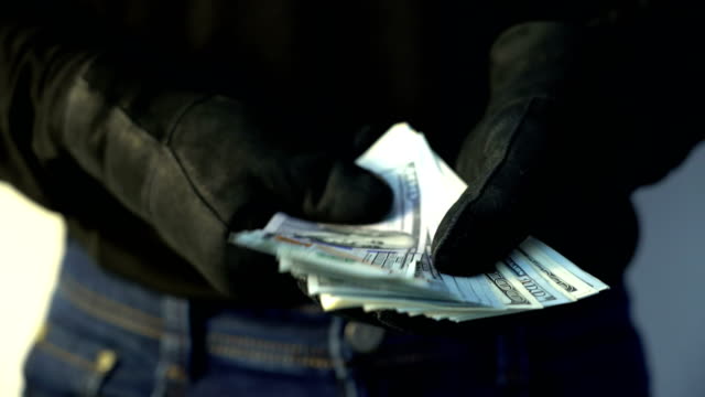 Kriminalität-Konzept-Mann-in-schwarzem-Lederhandschuhe-halten-Haufen-Geld