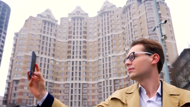 Closeup-Portrait-von-attraktiven-kaukasischen-Mann-unter-video-der-Stadt-auf-dem-Handy-auf-den-Hintergrund-oder-die-städtischen-Hochhäusern