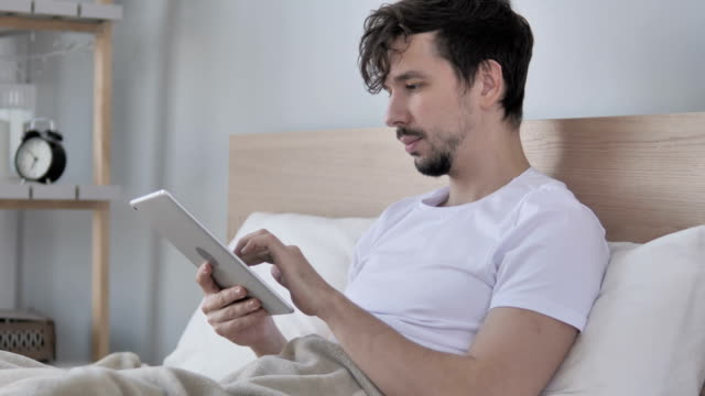 Junge-Mann-mittels-Tablet-beim-liegen-im-Bett