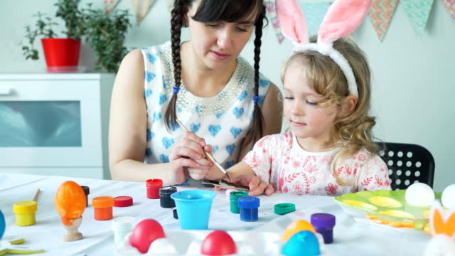 Pequeña-niña-pintura-de-madera-conejo-de-Pascua-con-mamá