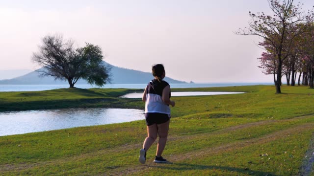 An-Asian-woman-jogging-in-natural-sunlight-in-the-evening.
She-is-trying-to-lose-weight-with-exercise.--concept-health-with-exercise.-Slow-Motion