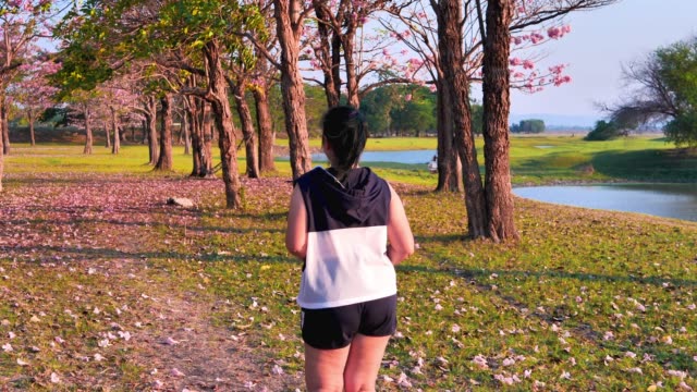 Una-mujer-asiática-gorda-corriendo-en-la-luz-del-sol-natural-por-la-noche.
Ella-está-tratando-de-perder-peso-con-el-ejercicio.--concepto-de-salud-con-ejercicio.-Cámara-lenta