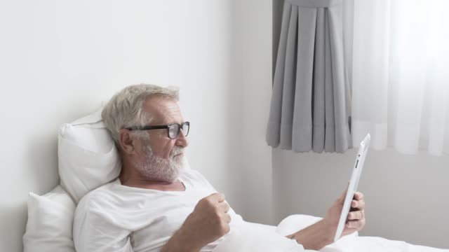 Großvater-oder-Seniorenmensch-mit-Tablet-Technik-und-aufmuntern-auf-dem-Bett