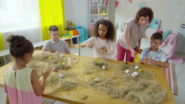 Niños-multiétnicos-decorar-huevos-de-Pascua-en-clase-de-arte