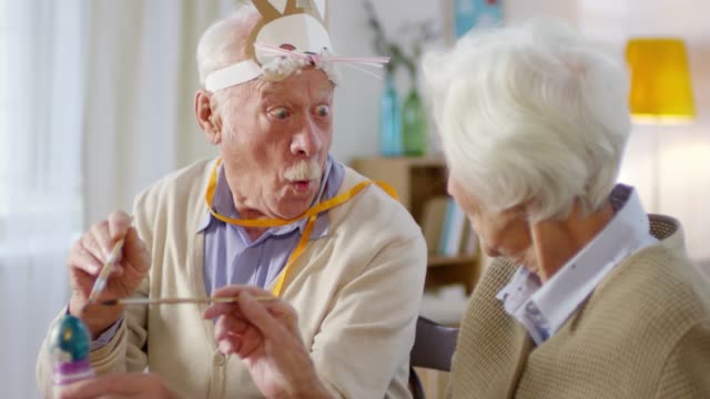 Elderly-Couple-Painting-Eggs-and-Laughing