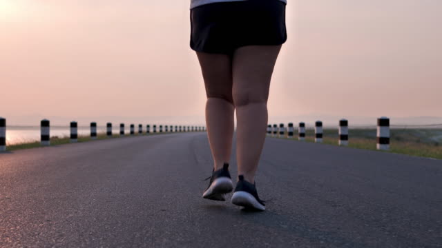 Overweight-Asian-women-jogging-in-the-street-in-the-early-morning-sunlight.-concept-of-losing-weight-with-exercise-for-health.-Slow-motion,-Bottom-view