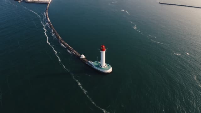 Aerial-shot-of-white-lighthouse-near-sea-port,-360-view