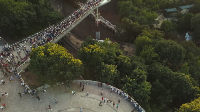 Eine-Menschenmenge-auf-einer-Fußgängerbrücke-ist-am-Frühlingsabend-zu-sehen.-Luftaufnahme.-Eine-neue-Fahrrad-Fußgängerbrücke-im-Zentrum-der-Hauptstadt-der-Ukraine,-der-Stadt-Kiew.-Ausflüge-und-Spaziergänge-für-Touristen