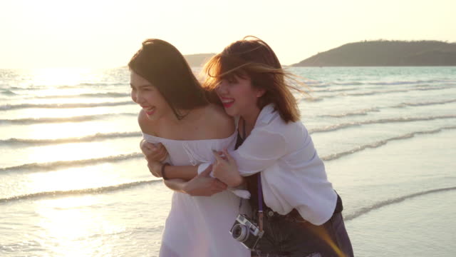 Joven-pareja-lesbiana-asiática-corriendo-en-la-playa.-Hermosas-mujeres-amigas-feliz-relax-divertirse-en-la-playa-cerca-del-mar-cuando-la-puesta-de-sol-en-la-noche.-Lifestyle-pareja-lesbiana-viaje-en-concepto-de-playa.