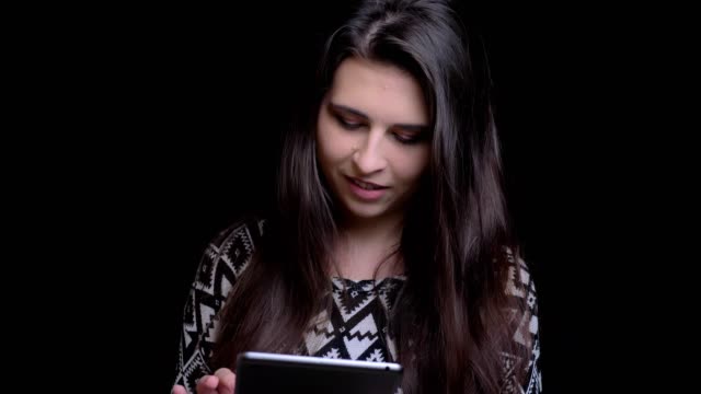 Nahaufnahme-von-jungen-attraktiven-kaukasischen-Frau-mit-dem-Tablet-sprechen-lächelnd-und-Blick-auf-die-Kamera-mit-Hintergrund-isoliert-auf-schwarz