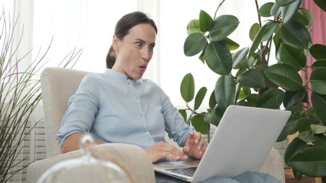 Mujer-emocionada-usando-computadora-portátil-en-casa