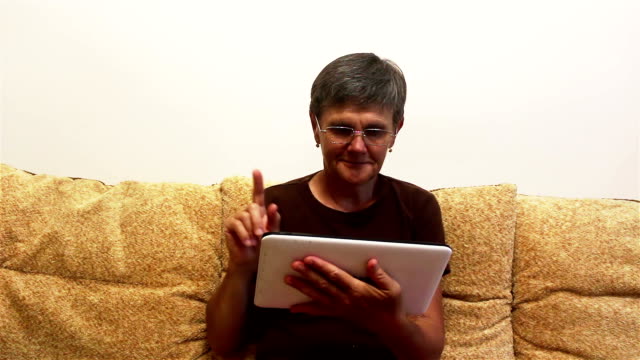 Attraktive-erwachsene-Frau-arbeiten-auf-ihrem-Tablet,-während-auf-einem-Sofa-zu-Hause-sitzen.
