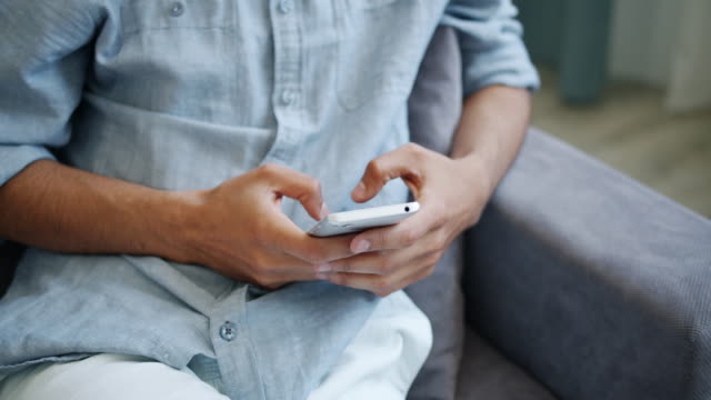 Nahaufnahme-männlicher-Hände-mit-Smartphone-berühren-Bildschirm-in-Innenräumen-zu-Hause
