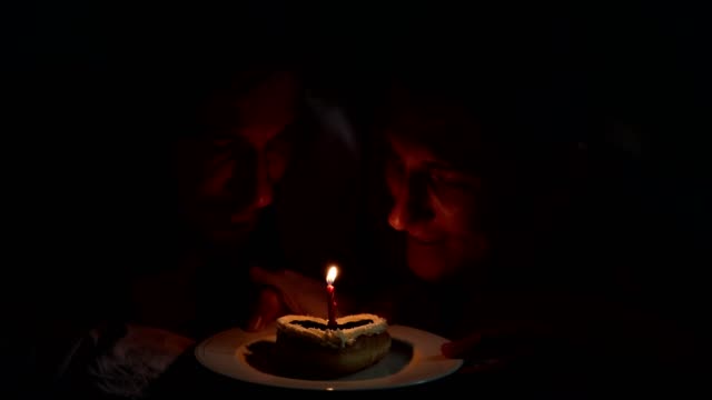 Gay-couple-enjoy-their-birthday-cake-together-in-bed.-Make-a-wish-and-blow-candle.