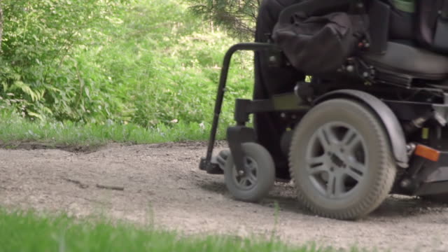 Lento-movimiento-del-hombre-en-una-silla-de-ruedas-que-sale-de-la-carretera-con-obstáculo-en-la-carretera.-discapacitados-concepto-problema