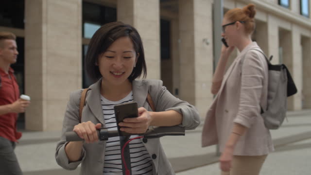 Asiatische-Frau-mit-E-Scooter-und-Smartphone