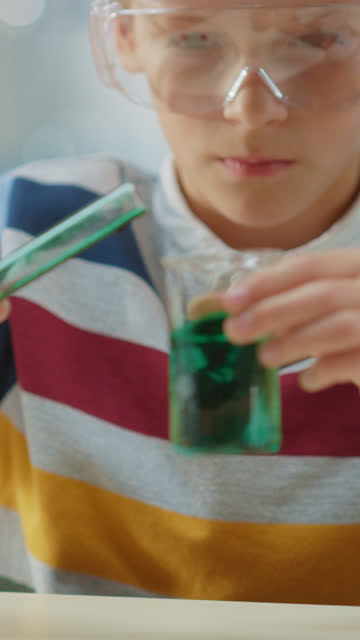 Cute-Little-Boy-in-Chemie-Klasse-MIxes-Chemikalien-und-Becher,-mehr-über-Wissenschaft-lernen.-Videomaterial-mit-vertikaler-Bildschirmausrichtung-9:18