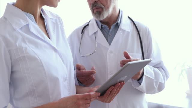 Medical-team-two-doctors-using-tablet,-shake-hands,-closeup