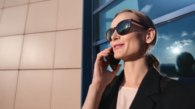 Smiling-face-of-joyful-businesswoman-discussing-work-use-telephone-outdoor.-4k-Dragon-RED-camera