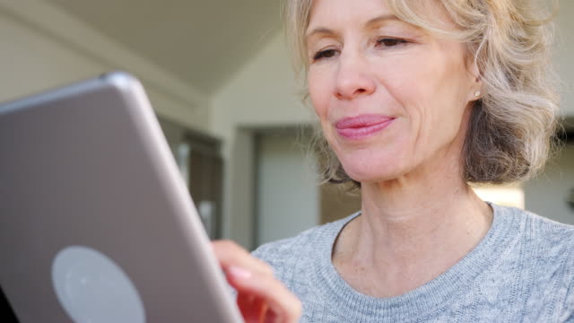 Mujer-madura-en-casa-comprando-productos-o-servicios-en-línea-usando-tableta-digital-y-tarjeta-de-crédito