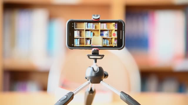 Ein-Mobiltelefon,-das-auf-einem-Stativ-montiert-ist,-wird-verwendet,-um-Studenten-online-in-der-Bibliothek-zu-unterrichten.