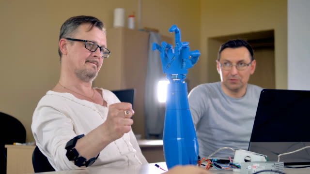 Mid-shot-of-the-two-men-testing-bionic-robotic-hand.