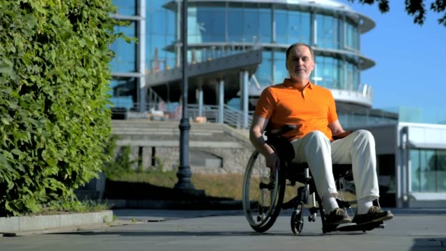 Pleasant-senior-man-sitting-in-the-wheelchair-outdoors