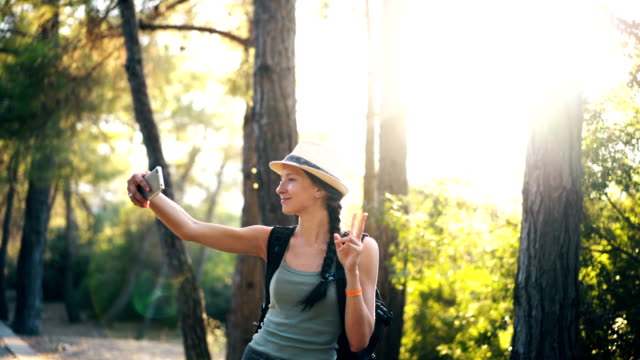 Niña-turismo-divertido-sombrero-tomando-selfie-fotos-con-la-cámara-del-smartphone-durante-el-viaje-y-autostop