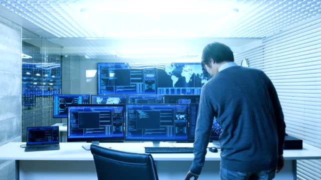 In-the-System-Control-Data-Center-Technician-Operates-Multiple-Screens-with-Neural-Network-and-Data-Mining-Activities.-Room-is-Light-and-Full-of-Monitors-with-Working-Neural-Network-on-Them.