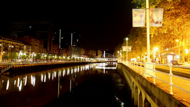 Romantic-night-promenade-along-waterfront-of-Nervion-river-in-Bilbao,-time-lapse
