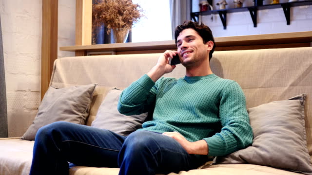 Young-Man-Talking-on-Phone,-Attending-Phone-Call-Sitting-at-Home