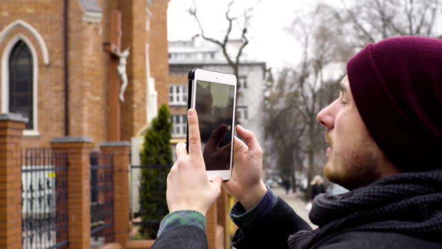 Ein-junger-Mann-nimmt-ein-Foto-von-der-Kirche-mit-einem-tablet