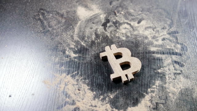 das-hölzerne-Bitcoin-Symbol-liegt-auf-einem-staubigen-Tisch