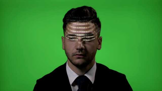 Attraktive-männliche-Hacker-gekleidet-wie-ein-Geschäftsmann-mit-Blockchain-Code-Ausdruck-auf-seinem-Gesicht-auf-einem-green-Screen-Hintergrund