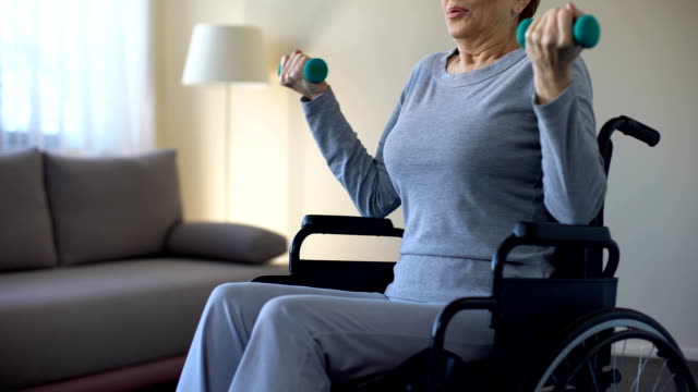 Mujer-Senior-en-silla-de-ruedas-levantando-pesas,-haciendo-ejercicios-en-casa,-recuperación