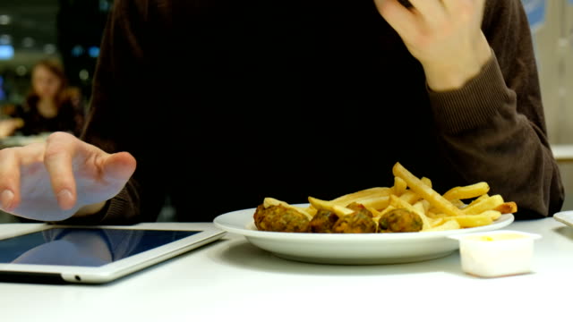 Gut-aussehender-Mann-essen-Fast-Food-und-Verwendungen-Tablet-Nahaufnahme