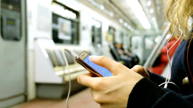 Mujer-utiliza-un-teléfono-en-el-primer-plano-de-metro