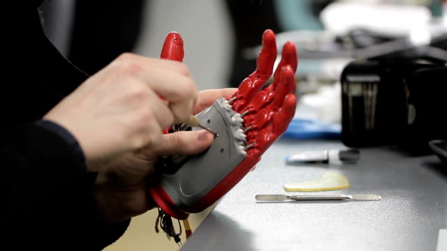 Man-arbeitet-mit-Hand-bionische-Prothese,-sitzt-am-Tisch-im-Innenbereich