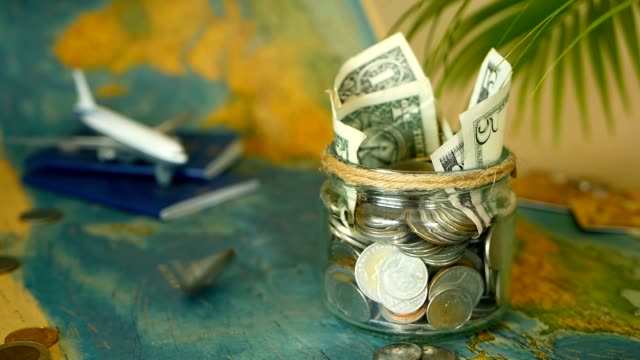 Travel-budget-concept.-Money-saved-for-vacation-in-glass-jar-on-world-map-background