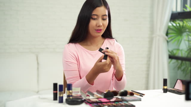 Beauty-blogger-present-beauty-cosmetics-while-sitting-in-front-camera-for-recording-video.-Beautiful-woman-use-brush-while-review-make-up-tutorial-broadcast-live-video-to-social-network-by-internet.