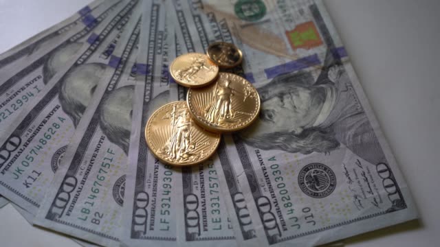 Monedas-de-oro-encima-de-cien-billetes-de-un-dólar-panorámica-de-vídeo