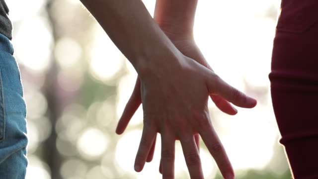 Nahaufnahme-von-zwei-LGBT-Liebhaber-verbinden-Hände-in-SLOW-MOTION-mit-Sonne-flare