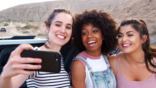 Female-friends-taking-selfies-during-a-break-on-road-trip