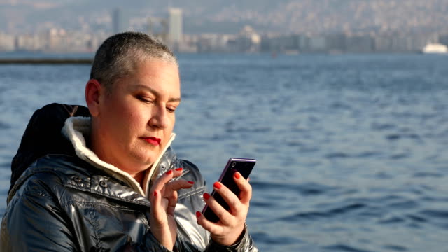 Mujer-con-smartphone-cerca-del-mar